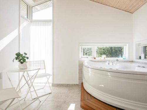 biała łazienka z wanną i stołem w obiekcie 6 person holiday home in Strandby w mieście Strandby