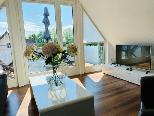 a living room with a vase of flowers on a table at Ferien-Apartment Haubentaucher im Naturschutzgebiet mit Privatstrand in Friedrichshafen