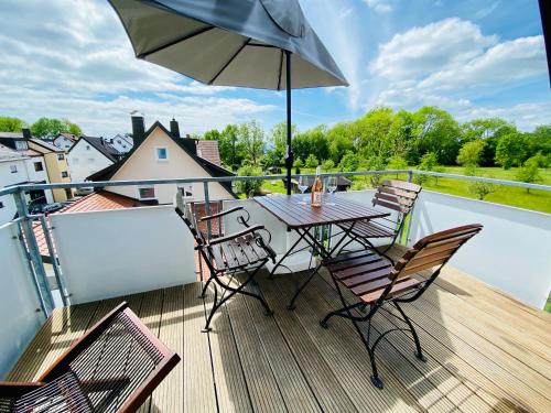 a table and chairs on a balcony with an umbrella at Ferien-Apartment Haubentaucher - mit priv Strandzugang in Friedrichshafen