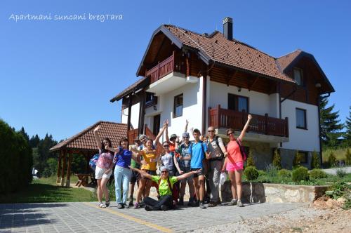 Un gruppo di persone che si trovano di fronte a una casa di Apartmani Suncani breg Tara a Mitrovac