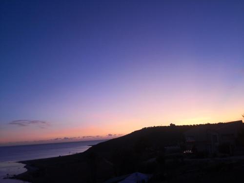a sunset over the ocean with a hill at Holiday Beach Lumia in Sciacca