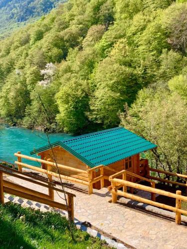 a picnic table with a blue roof next to a lake at Rafting Tara Camp Highlander in Bastasi