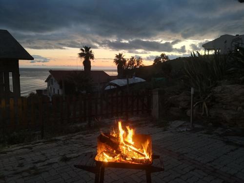 a fire pit on a patio with the sunset in the background at Holiday Beach Lumia in Sciacca