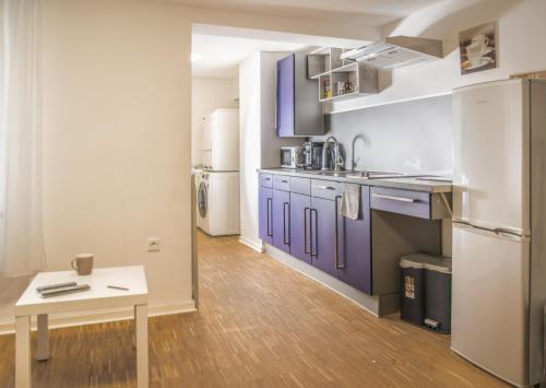 a kitchen with purple cabinets and a wooden floor at Altstadt Apartment Alisa in Düsseldorf