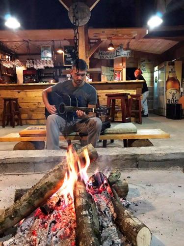 a man playing a guitar over a fire at Rafting Tara Camp Highlander in Bastasi
