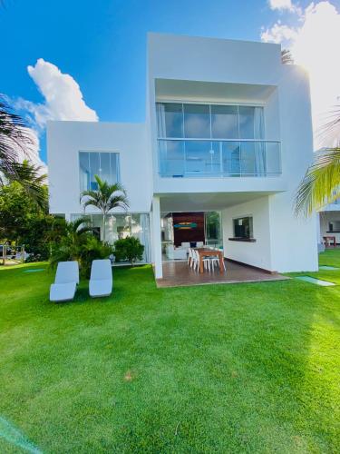 a white house with a green yard with white chairs at B Blue Beachouses in Itacimirim