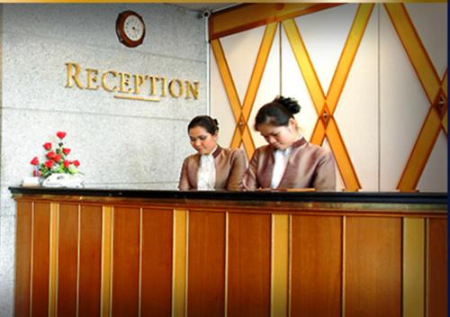 two women standing at a reception desk at Majestic Suites Hotel in Bangkok