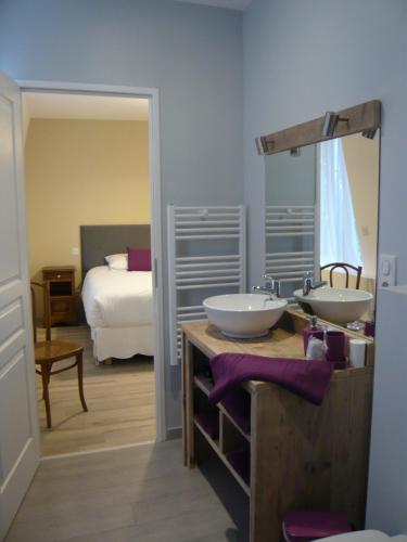 a bathroom with two sinks and a bedroom with a bed at Chambres d'Hotes Noir Lion in Péronne