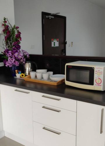 a kitchen counter with a microwave and bowls and flowers at Coco View Hotel in Samut Songkhram