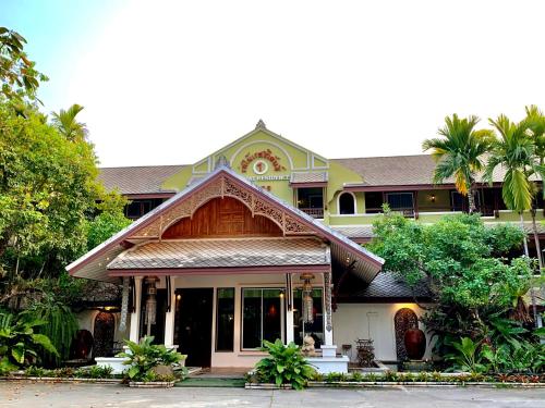 a house with a building with palm trees at Rommai Greenpark in Lampang
