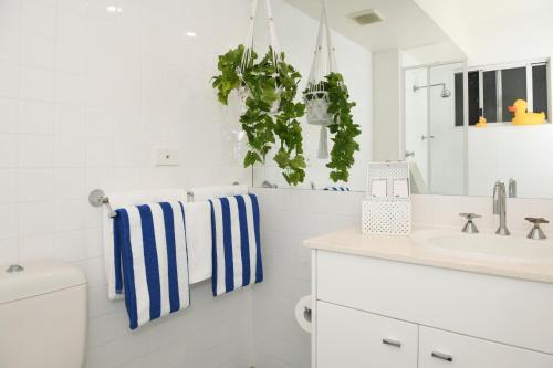 a white bathroom with blue and white towels at Terrigal Pacific Coastal Retreat in Terrigal