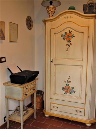 a white cabinet with a painting on it next to a table at La Pietra Rara B&B in Montone