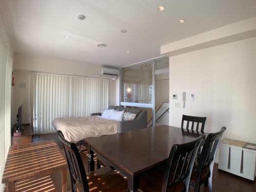 a dining room with a table and a bed at Seaside Condominium Rana Chatan in Chatan