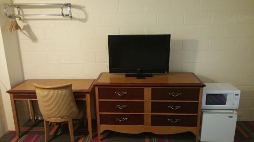 a desk with a television on top of a dresser at Thunder Bird Motel in Mountain Home