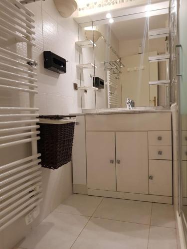 une salle de bain blanche avec un lavabo et un miroir dans l'établissement Appartement Face a la Mer, à Pornic