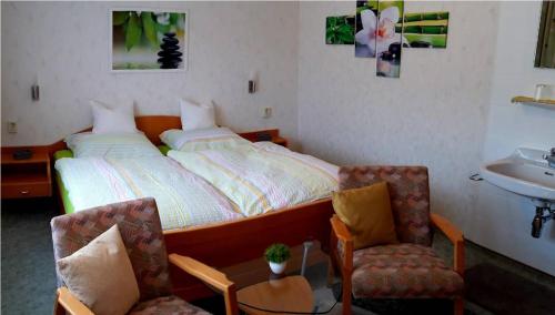 een slaapkamer met een bed, 2 stoelen en een wastafel bij Ferienwohnung Günther in Baiersbronn