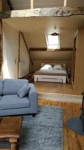 a living room with a bed and a blue couch at Le Galet "Chez Jacquie et Fifi" in Mont-Dauphin