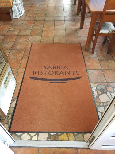 a welcome mat on a tile floor in a restaurant at Sabbia Ristorante - Reštaurácia a Ubytovanie Prievidza in Prievidza