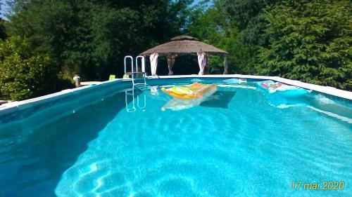 - une piscine avec un kiosque en arrière-plan dans l'établissement Le Clos des Palombes WIFI CLIMATISATION, à Saint-Pierre-du-Mont