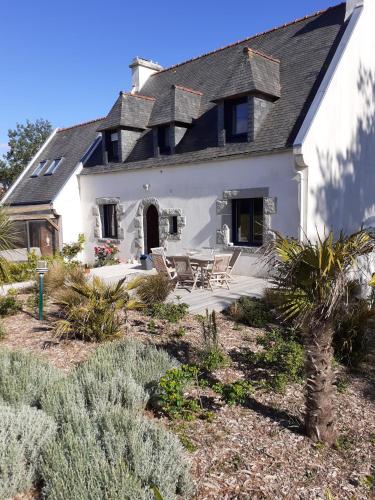une maison blanche avec une table et des chaises dans l'établissement LE CLOS DES ABERS, à Saint-Pabu
