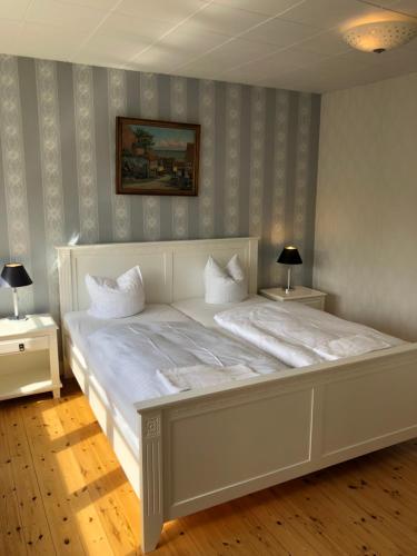 a large white bed in a room with two tables at Sleep & Coffee Apartments in Præstø