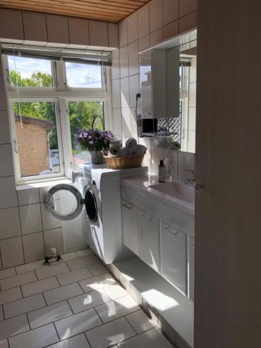 a white bathroom with a sink and a window at Sleep & Coffee Apartments in Præstø