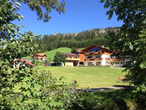 a large building on a grassy field with trees at Sonnleiten - Guggerhof - Villa Sonnenwies in Tannheim