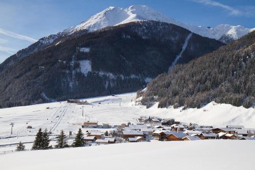 a small town in the snow with a snow covered mountain at Ferienhaus Aurora in Kals am Großglockner