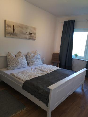 a white bed in a bedroom with a window at Lüttje Heide-Huus in Soltau
