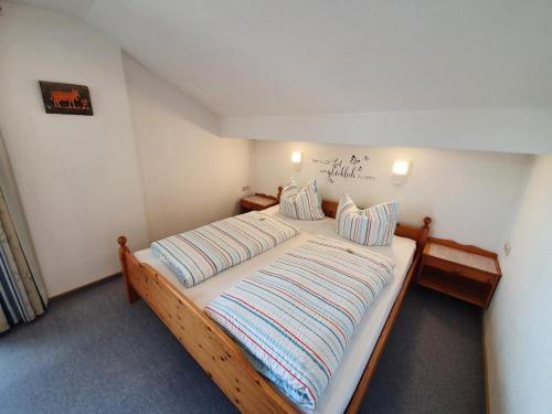 a bedroom with a wooden bed with striped pillows at Haus Bayrhof in Hopferau