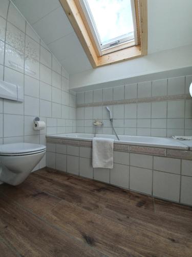 a bathroom with a tub and a toilet and a window at Haus Bayrhof in Hopferau
