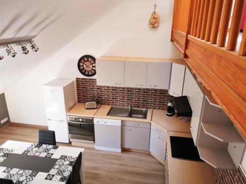 une cuisine avec des placards blancs et une horloge murale dans l'établissement L'Ancre Marine, à Cancale