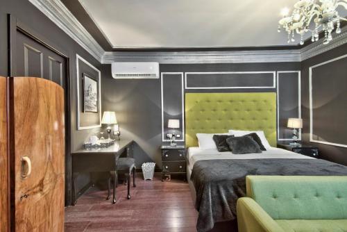a bedroom with a bed with a green headboard and a desk at Julina Boutique Living in Mosta