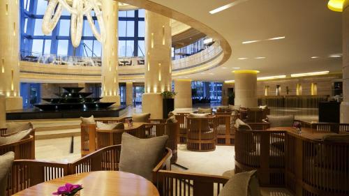 a restaurant with wooden tables and chairs and a chandelier at Kempinski Hotel Taiyuan in Taiyuan