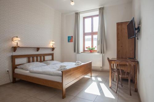 um quarto com uma cama, uma mesa e uma janela em Penzion a restaurace U Hájků em Nové Dvory