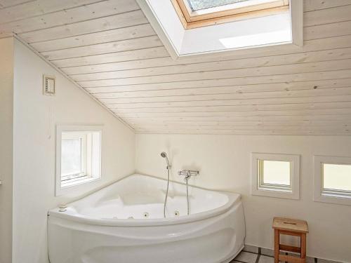 a white bath tub in a bathroom with a skylight at Four-Bedroom Holiday home in Nexø 14 in Spidsegård