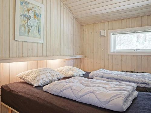 two beds in a room with wooden walls and a window at Four-Bedroom Holiday home in Nexø 14 in Spidsegård