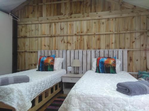 twee bedden in een kamer met houten wanden bij African Sky's the Limit - Budget, Quiet, Peaceful Self-Catering in Durban