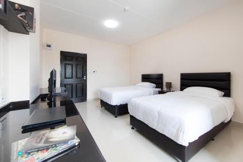 a bedroom with two beds and a desk with a television at JJ Residence in Pluak Daeng