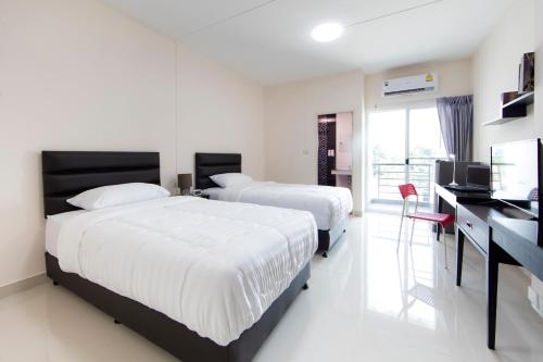 a bedroom with two beds and a desk with a television at JJ Residence in Pluak Daeng