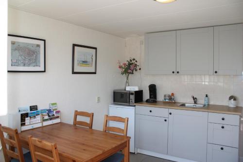 a kitchen with white cabinets and a wooden table at B&B Kleine Vliet in Medemblik