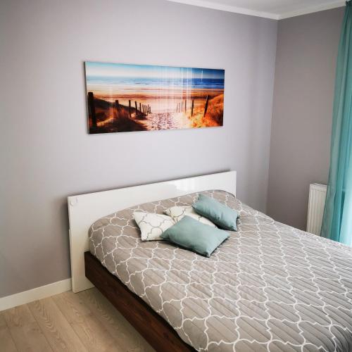 a bedroom with a bed with a picture on the wall at Apartament IDEAL in Dziwnów