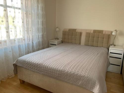 a bedroom with a large bed and a window at Baltas apartamentas in Juodkrantė