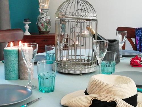 a table with a bird cage with a hat and glasses at les roches du Cabellou 150M de la mer in Concarneau