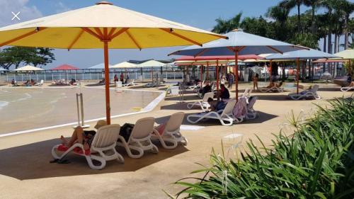 a group of chairs and umbrellas next to a beach at Darwin City Harbour views-Situated above the OAK Restaurant in Darwin