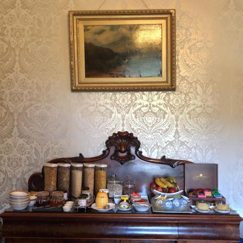 a table with food on it with a picture on the wall at Elm Grove Country House in Tenby