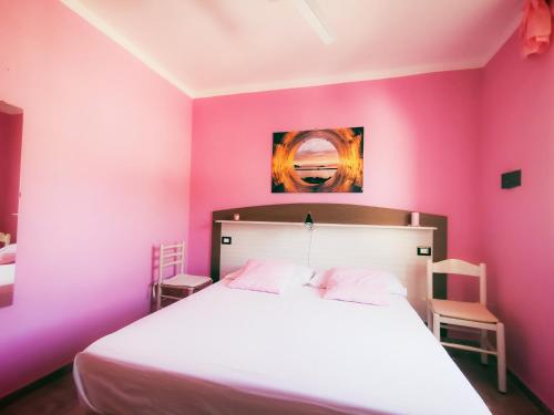 サンタ・マリア・ディ・カステッラバーテにあるLe Sirene Castellabateのピンクの壁のベッドルーム(白いベッド付)
