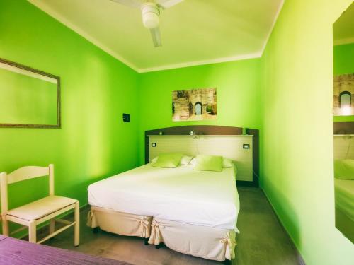 a green bedroom with a bed and a chair at Le Sirene Castellabate in Santa Maria di Castellabate
