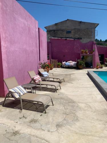 um grupo de cadeiras sentadas ao lado de uma parede rosa em São Miguel House , Casa do Carvalhal em Santarém
