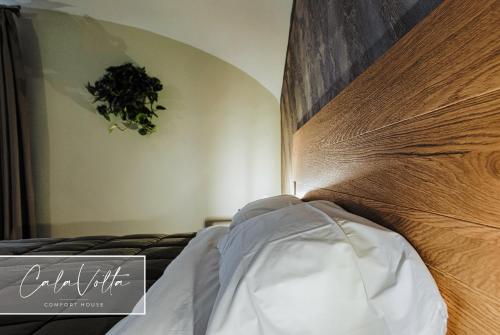 a bedroom with a bed with a wooden head board at Cala Volta Comfort House in Torre del Greco